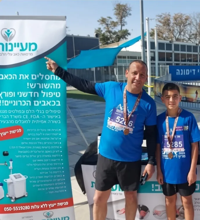 אב ובנו עם מדליות ליד שלט מעיינות באירוע ריצה